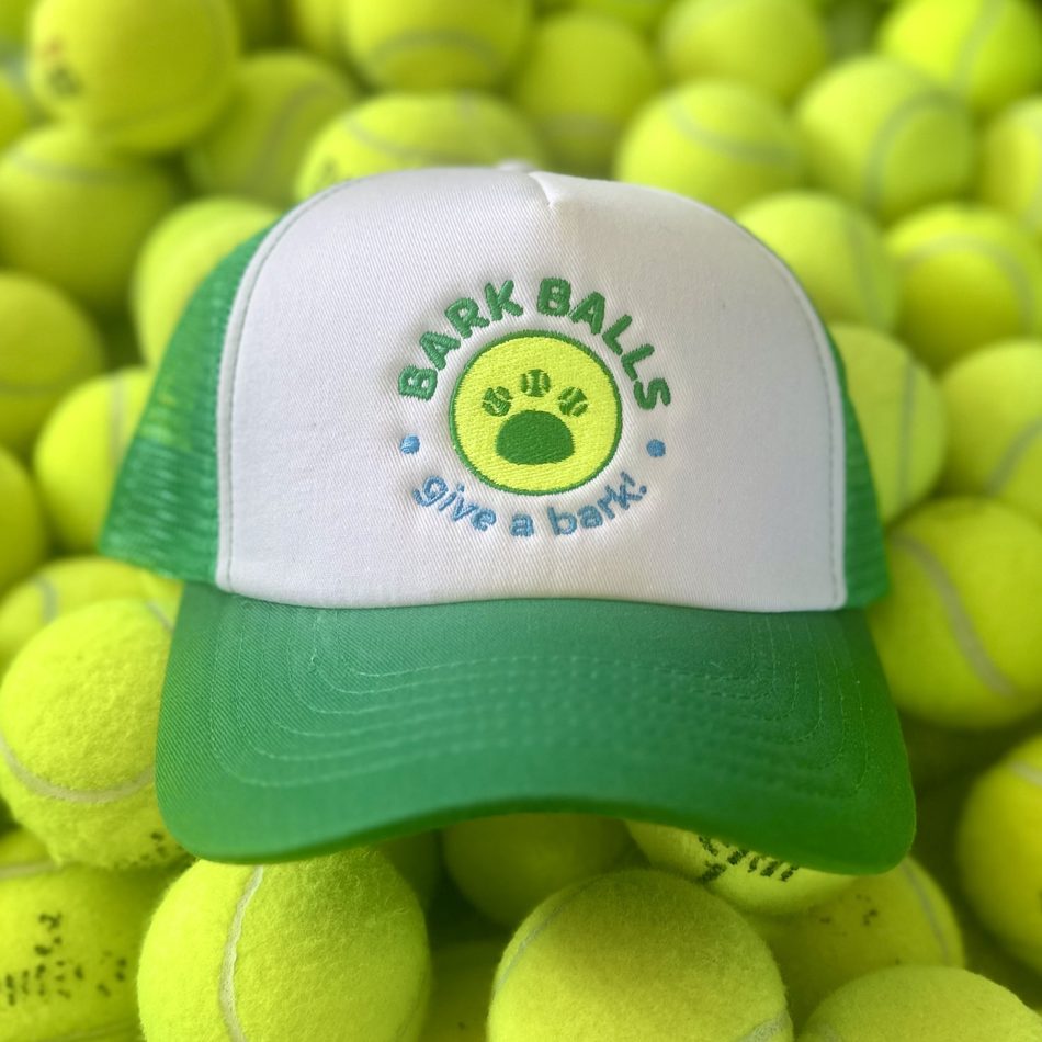 The Bark Balls trucker hat resting on a pile of tennis balls